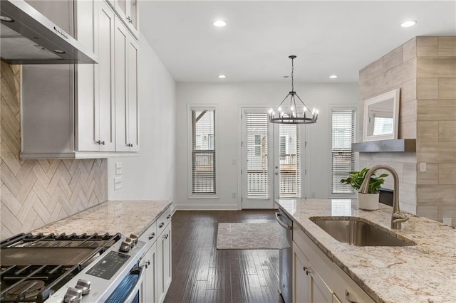 kitchen featuring wall chimney exhaust hood, sink, appliances with stainless steel finishes, light stone countertops, and white cabinets