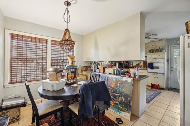 tiled dining space with ceiling fan with notable chandelier