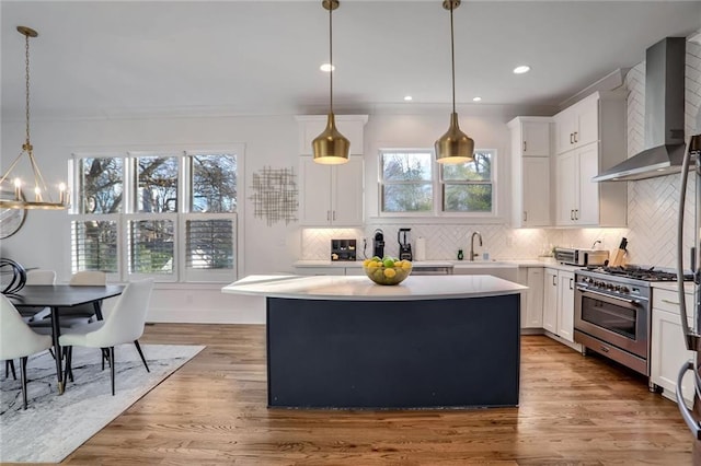 kitchen with white cabinets, pendant lighting, wall chimney range hood, and stainless steel range