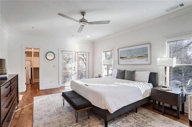 bedroom featuring ornamental molding, ceiling fan, a spacious closet, multiple windows, and light hardwood / wood-style floors