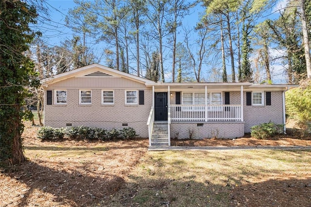 ranch-style house featuring crawl space, covered porch, brick siding, and a front lawn