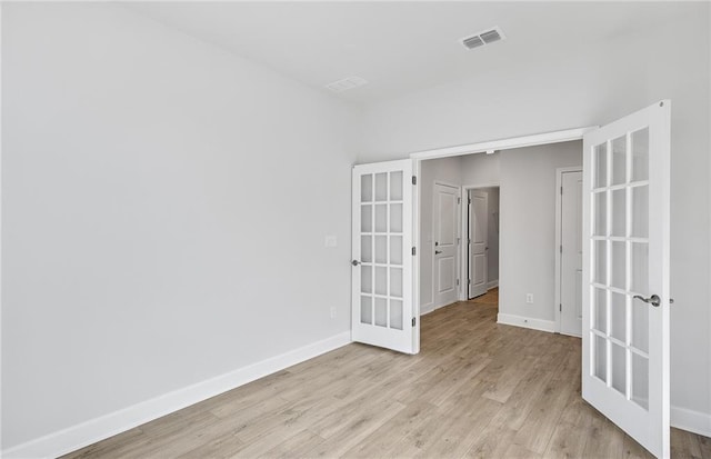 spare room with french doors and light wood-type flooring