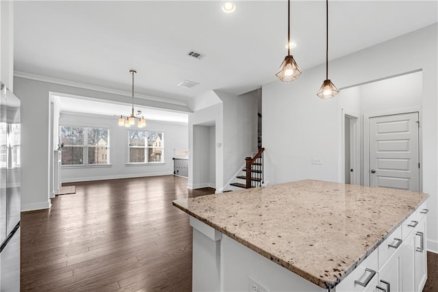 kitchen with white cabinets, a kitchen island, dark wood-type flooring, hanging light fixtures, and light stone countertops