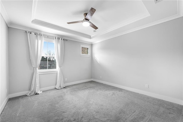 empty room featuring ornamental molding, carpet, a raised ceiling, and baseboards