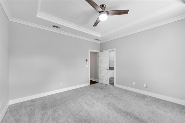 spare room with carpet floors, a tray ceiling, visible vents, and crown molding