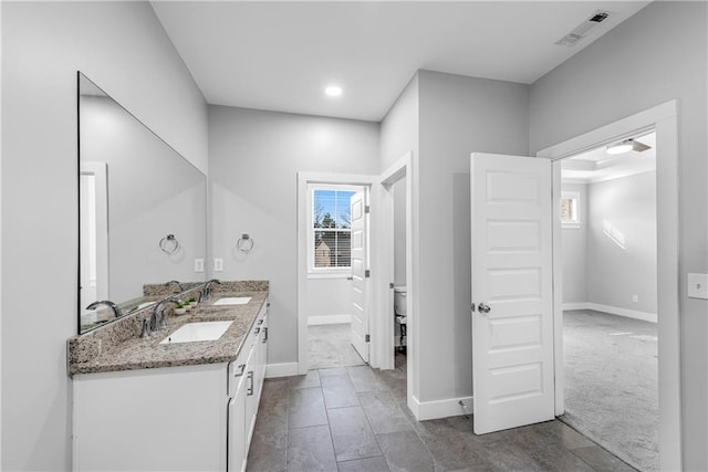 bathroom with toilet, plenty of natural light, a sink, and visible vents