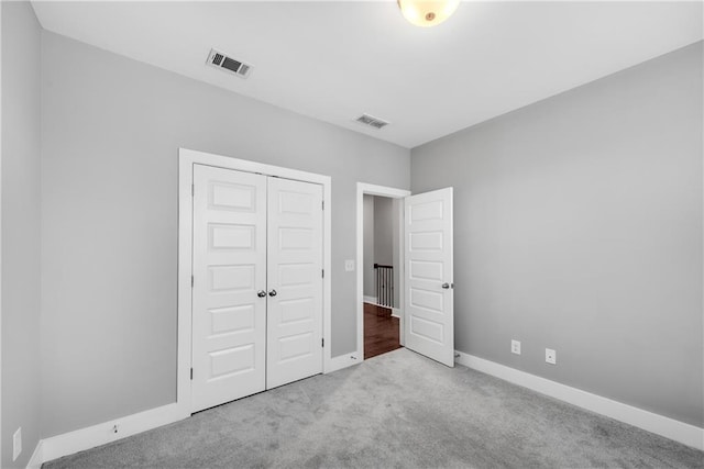 unfurnished bedroom with light carpet, baseboards, visible vents, and a closet