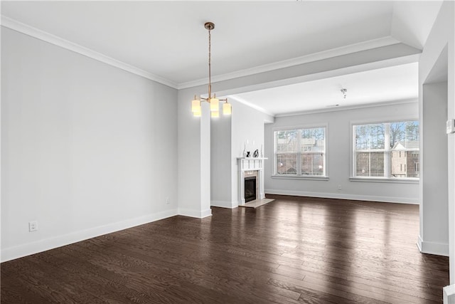 unfurnished living room featuring baseboards, dark wood finished floors, a fireplace with flush hearth, ornamental molding, and a notable chandelier