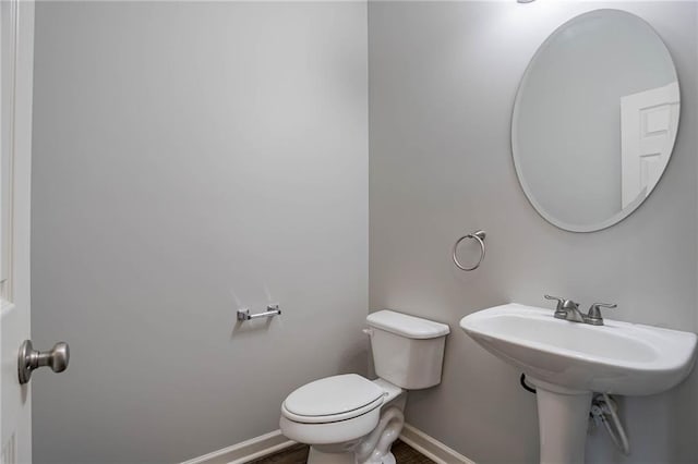 bathroom with wood finished floors, toilet, baseboards, and a sink