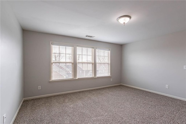 spare room with carpet flooring, baseboards, and visible vents