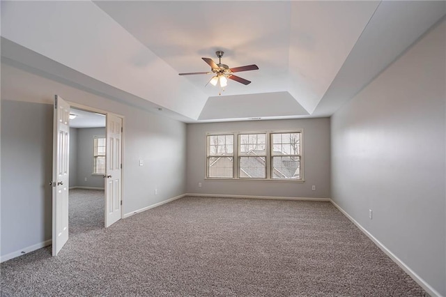 empty room with carpet flooring, baseboards, a raised ceiling, and ceiling fan