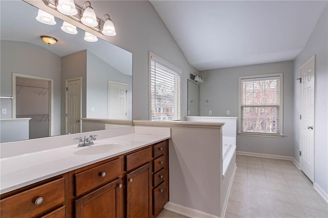 bathroom featuring vanity, lofted ceiling, baseboards, and a wealth of natural light