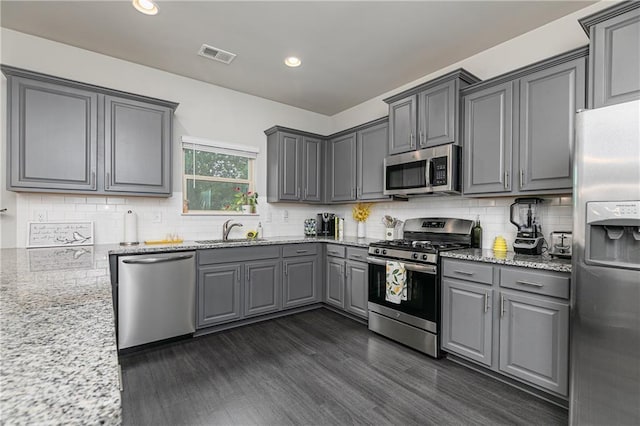 3302 Bellingham Way, Lithia Springs, GA 30122 - kitchen with appliances with stainless steel finishes, gray cabinetry, light stone counters, decorative backsplash, and dark wood-style floors