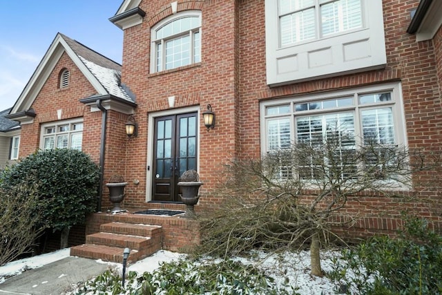 snow covered property entrance featuring french doors