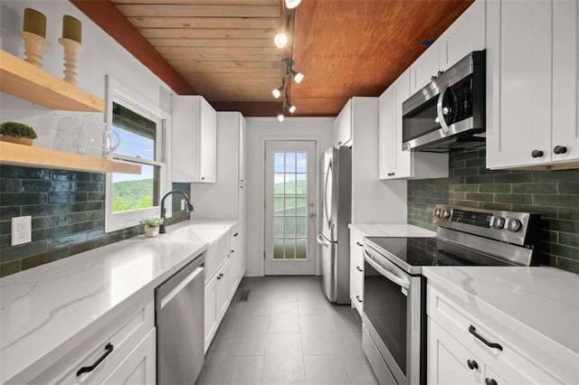 kitchen featuring rail lighting, wooden ceiling, backsplash, white cabinets, and appliances with stainless steel finishes