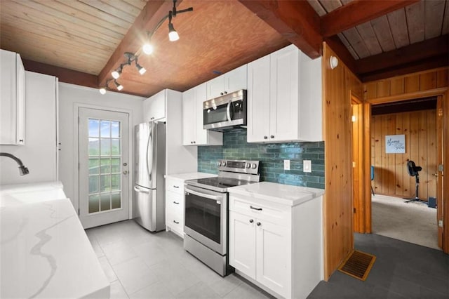 kitchen with a sink, rail lighting, light stone counters, wooden ceiling, and appliances with stainless steel finishes