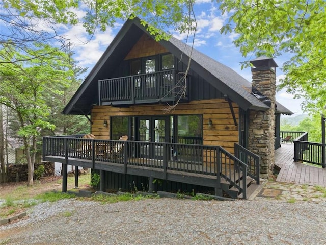 rear view of house featuring a chimney, a wooden deck, and french doors