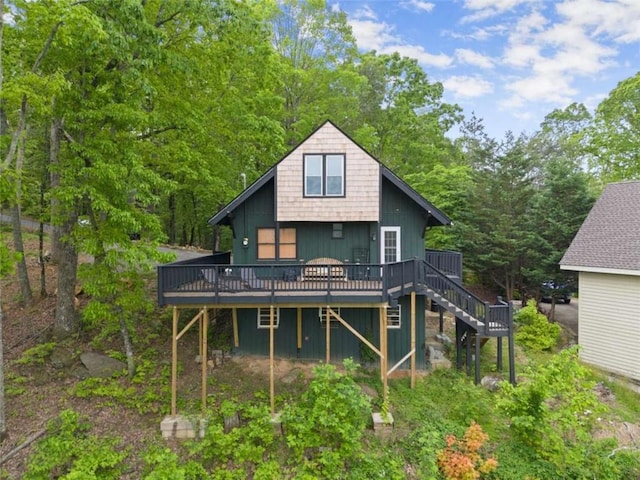 back of house featuring a wooden deck, stairs, a forest view, and board and batten siding
