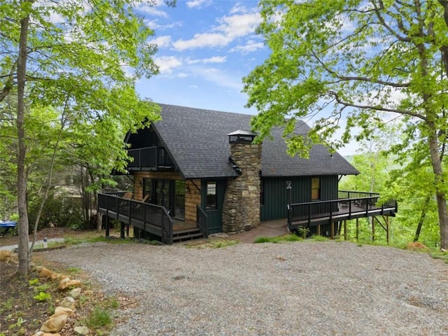 view of front of home featuring a chimney, board and batten siding, a wooden deck, and a shingled roof