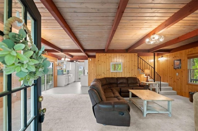 living area with stairway, wood walls, beamed ceiling, and plenty of natural light