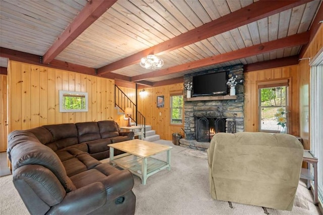 carpeted living area featuring wood ceiling, stairs, wood walls, beamed ceiling, and a fireplace