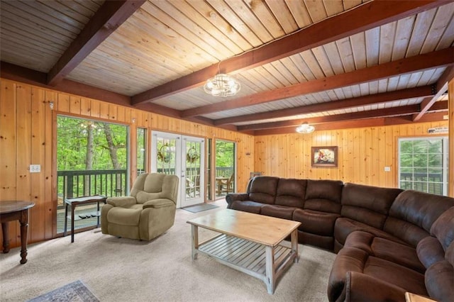 living room featuring beamed ceiling, carpet flooring, wood walls, and a wealth of natural light