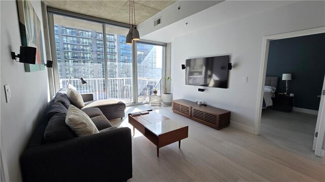 living room with visible vents, wood finished floors, baseboards, and expansive windows