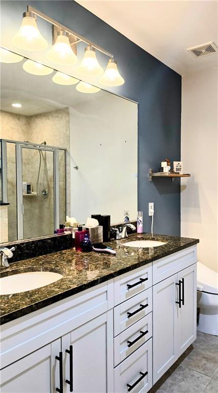 full bath with a sink, visible vents, double vanity, and a shower stall