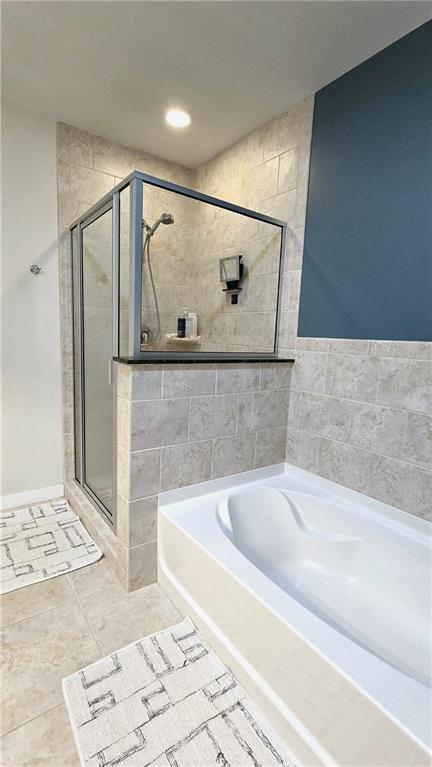 bathroom featuring tile patterned floors, a shower stall, and a garden tub