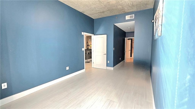 empty room featuring visible vents, baseboards, and wood finished floors