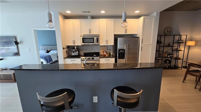 kitchen with backsplash, a kitchen breakfast bar, stainless steel appliances, and white cabinetry