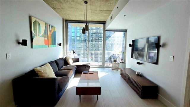 living area with a wall of windows, wood finished floors, visible vents, and baseboards