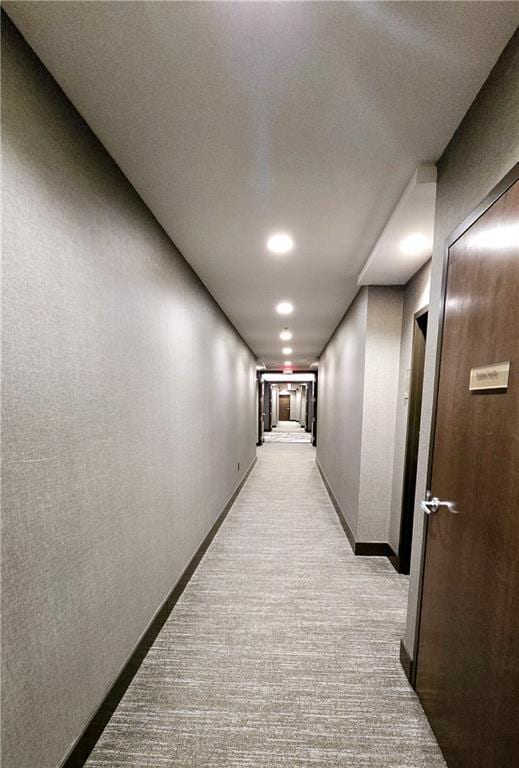 hallway featuring baseboards and light colored carpet