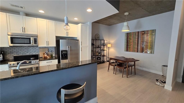 kitchen featuring light wood-type flooring, visible vents, tasteful backsplash, appliances with stainless steel finishes, and white cabinets