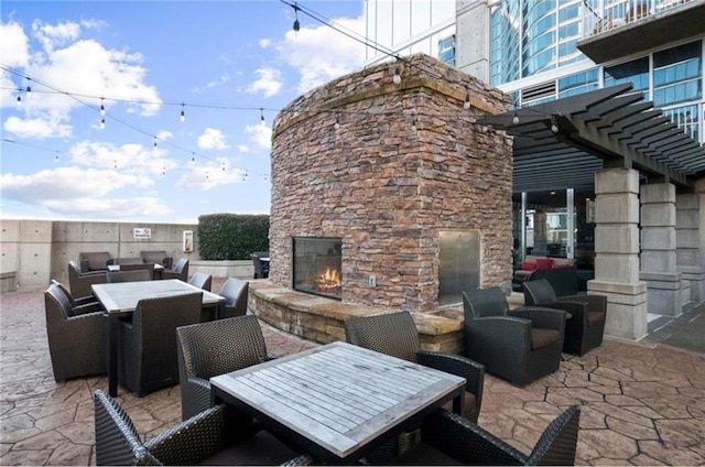 view of patio with outdoor dining area, a pergola, and an outdoor living space with a fireplace