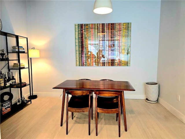 dining space with baseboards and wood finished floors