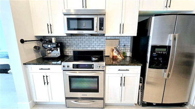 kitchen with dark stone countertops, white cabinets, backsplash, and appliances with stainless steel finishes