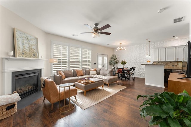 living room featuring dark hardwood / wood-style flooring and ceiling fan with notable chandelier