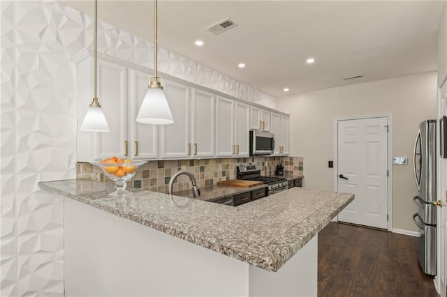 kitchen featuring appliances with stainless steel finishes, white cabinetry, hanging light fixtures, light stone counters, and kitchen peninsula