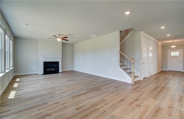 unfurnished living room featuring recessed lighting, a fireplace with flush hearth, baseboards, stairs, and light wood-type flooring