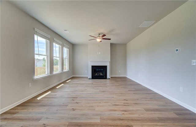 unfurnished living room with baseboards, a fireplace with flush hearth, visible vents, and light wood-style floors