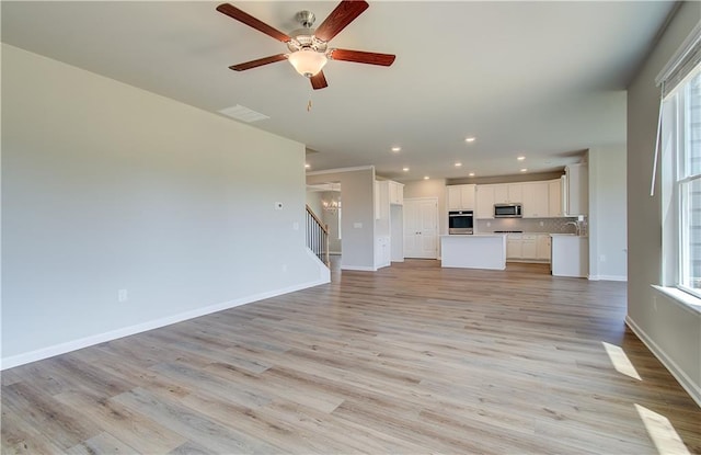 unfurnished living room with recessed lighting, visible vents, baseboards, stairs, and light wood-type flooring