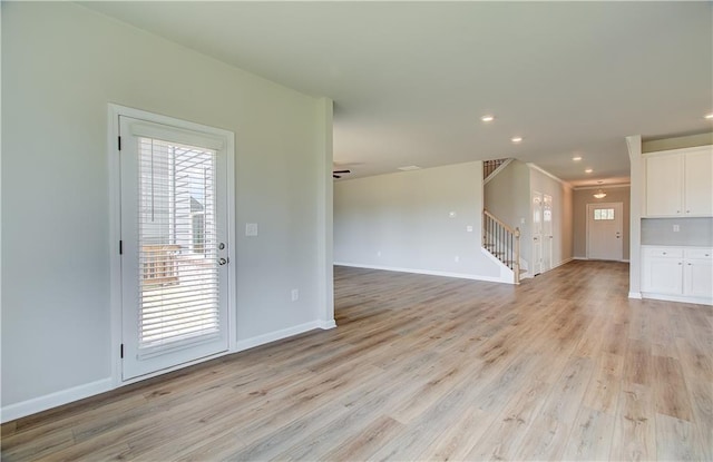 unfurnished living room featuring light wood-style floors, recessed lighting, baseboards, and stairs