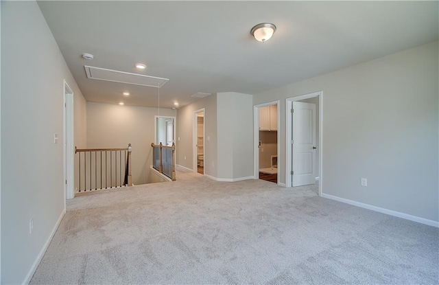 carpeted empty room with recessed lighting, attic access, and baseboards