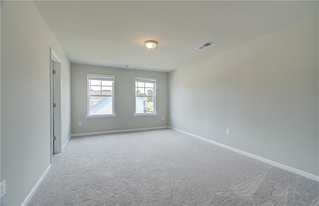 empty room featuring baseboards, visible vents, and light colored carpet