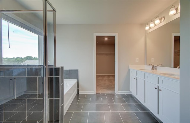 full bath featuring double vanity, a spacious closet, a sink, tile patterned flooring, and a bath