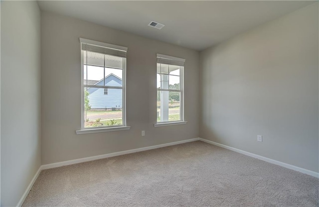 spare room featuring carpet, visible vents, and baseboards