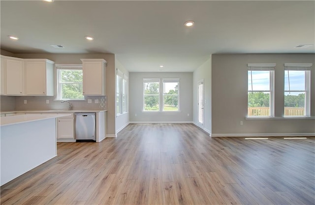 kitchen featuring light wood finished floors, tasteful backsplash, light countertops, open floor plan, and dishwasher