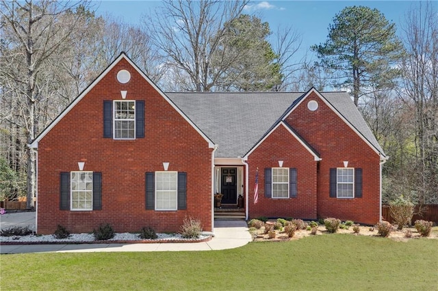 traditional-style home featuring fence, a front lawn, and brick siding