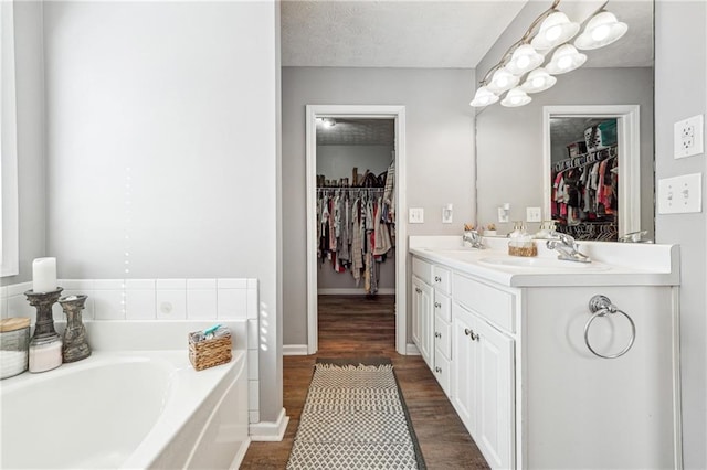 full bathroom featuring a garden tub, double vanity, wood finished floors, and a sink